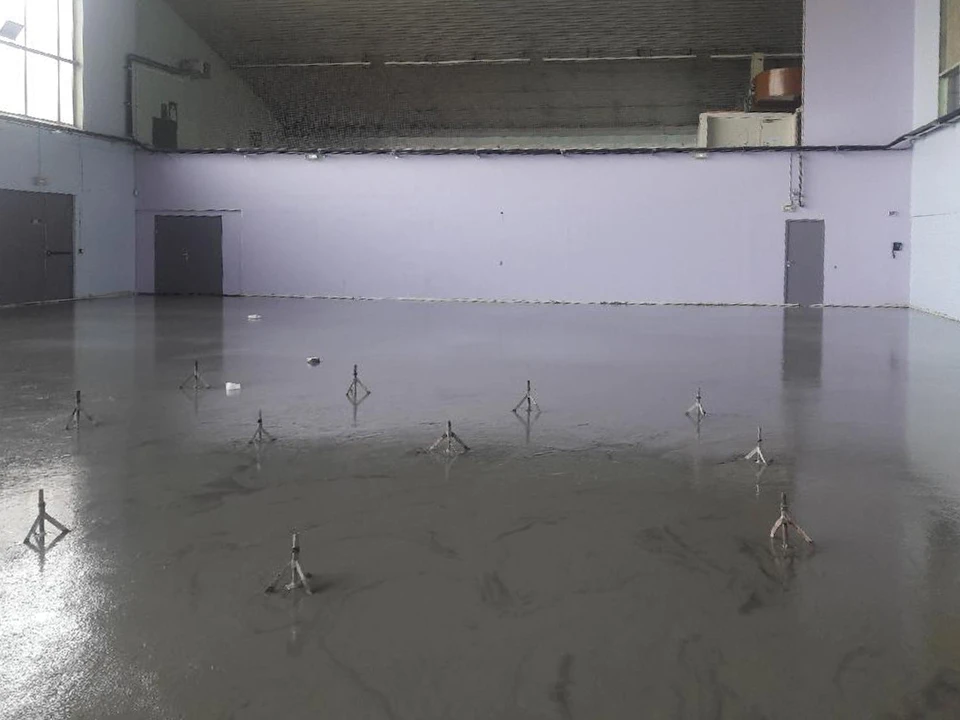 Ouvrier appliquant un revêtement de sol liquide autonivelant dans un intérieur résidentiel